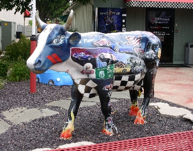 [Cow statue with car scenes painted on its side.]