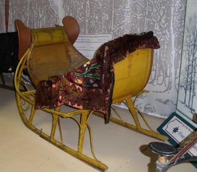 [Wooden sleigh with blanket draped on it.]